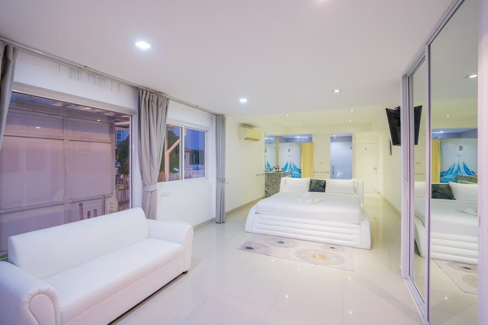 Royal Beach X Pool Villa bedroom suite in Pattaya. White platform bed, sofa, and mirrored closet.