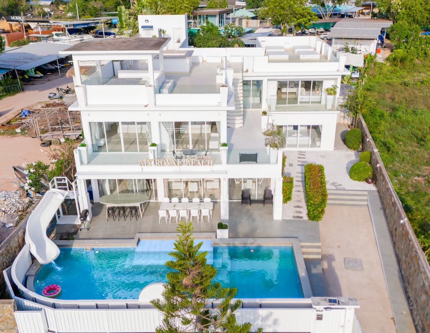 Aerial view of Royal Beach X Pool Villa, ติดทะเลนาจอมเทียน พัทยาใต้. Modern white villa with pool, slide, and outdoor dining.