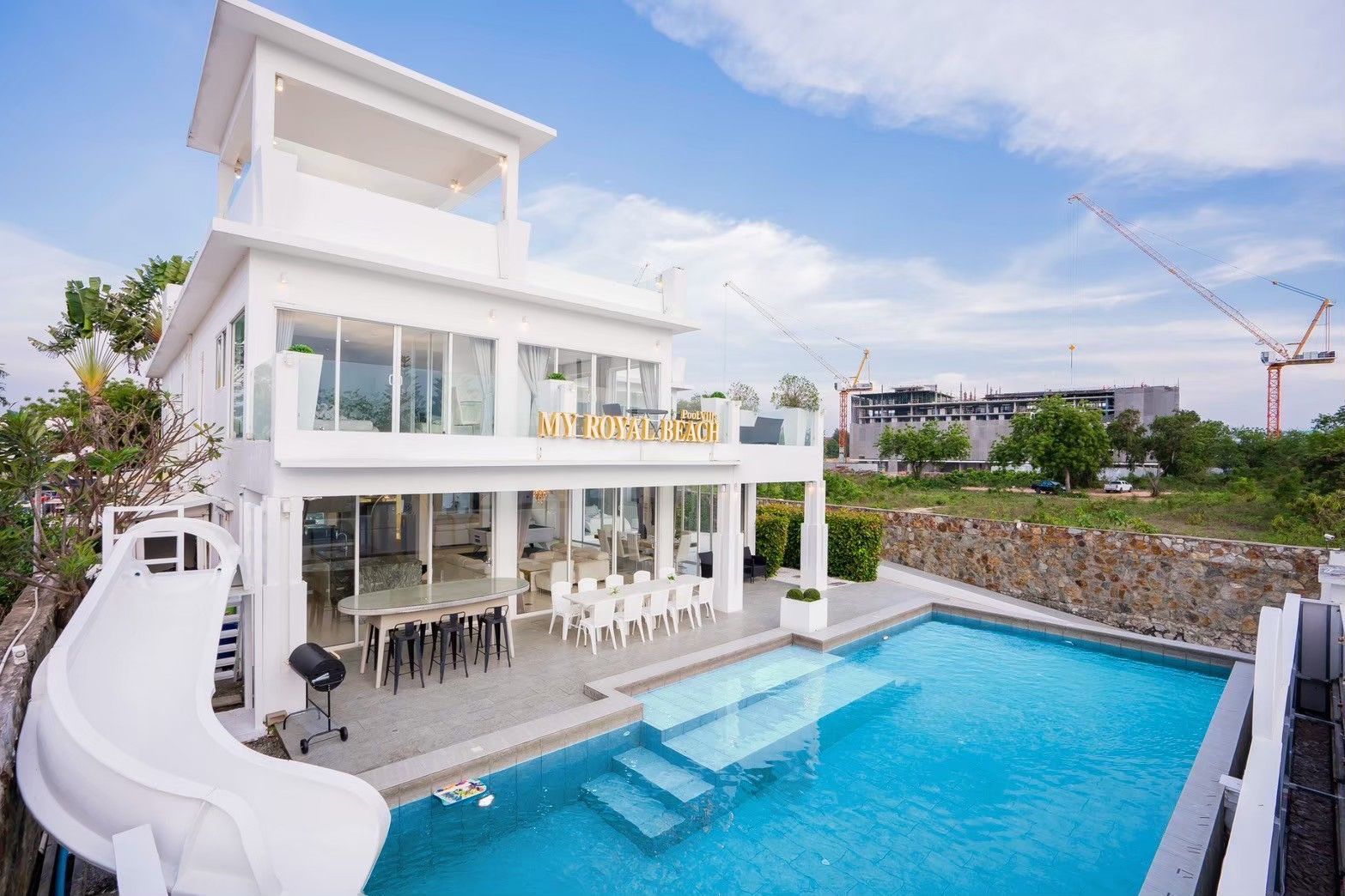 Exterior of Royal Beach X Pool Villa, ติดทะเลนาจอมเทียน พัทยาใต้, featuring a pool, slide, and outdoor dining.