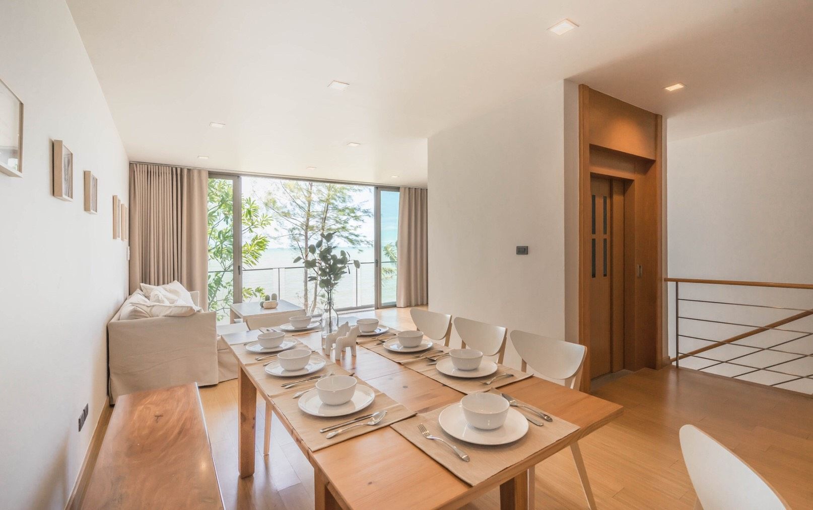 Dining table set for eight at Sand Beachfront Exclusive Villa, overlooking the ocean in North Pattaya, Thailand.