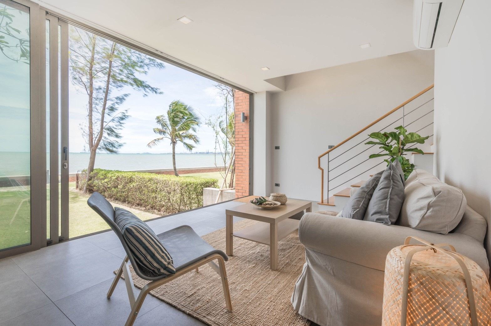 Living room with ocean view at Sand Beachfront Exclusive Villa, ติดทะเลพัทยาเหนือ บางละมุง. Sofa, chair, and sliding glass do