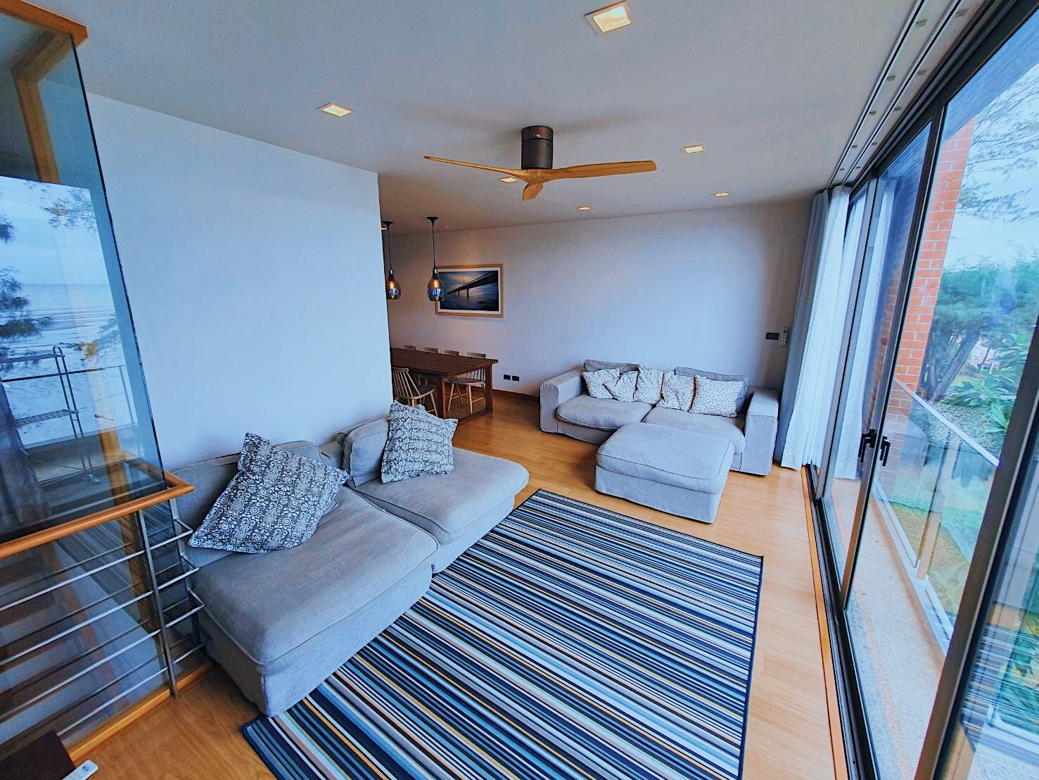 Living area with sectional sofa and striped rug at Sand Beachfront Pool Villa III, Pattaya. View of the ocean.