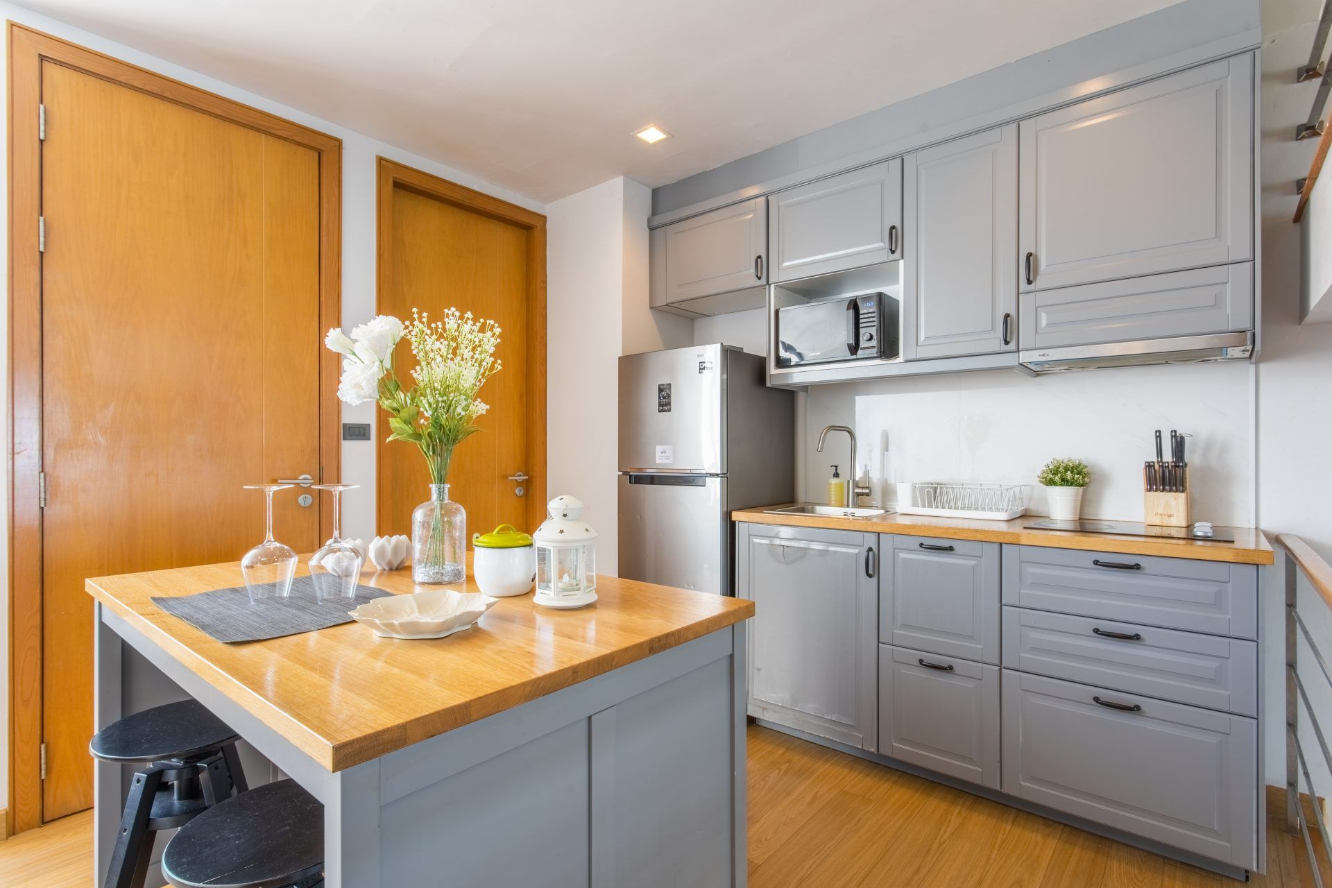 Sand Beachfront Villa IV kitchen in พัทยาเหนือ. Island with stools, grey cabinets, stainless steel fridge, and wood floors.