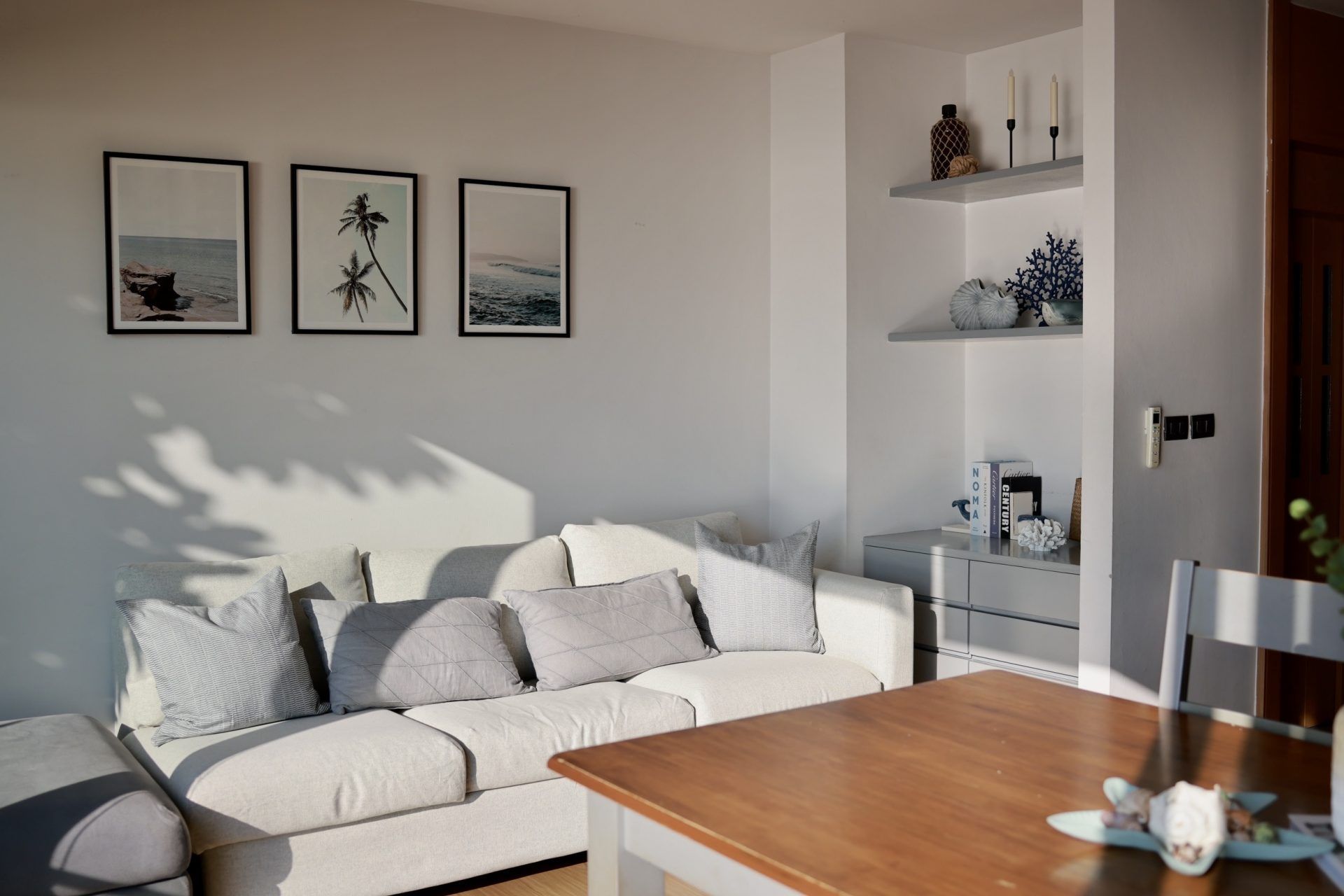 Living area at Sand Beachfront Villa IV, พัทยาเหนือ. Features a sofa, wall art, and decorative shelves.