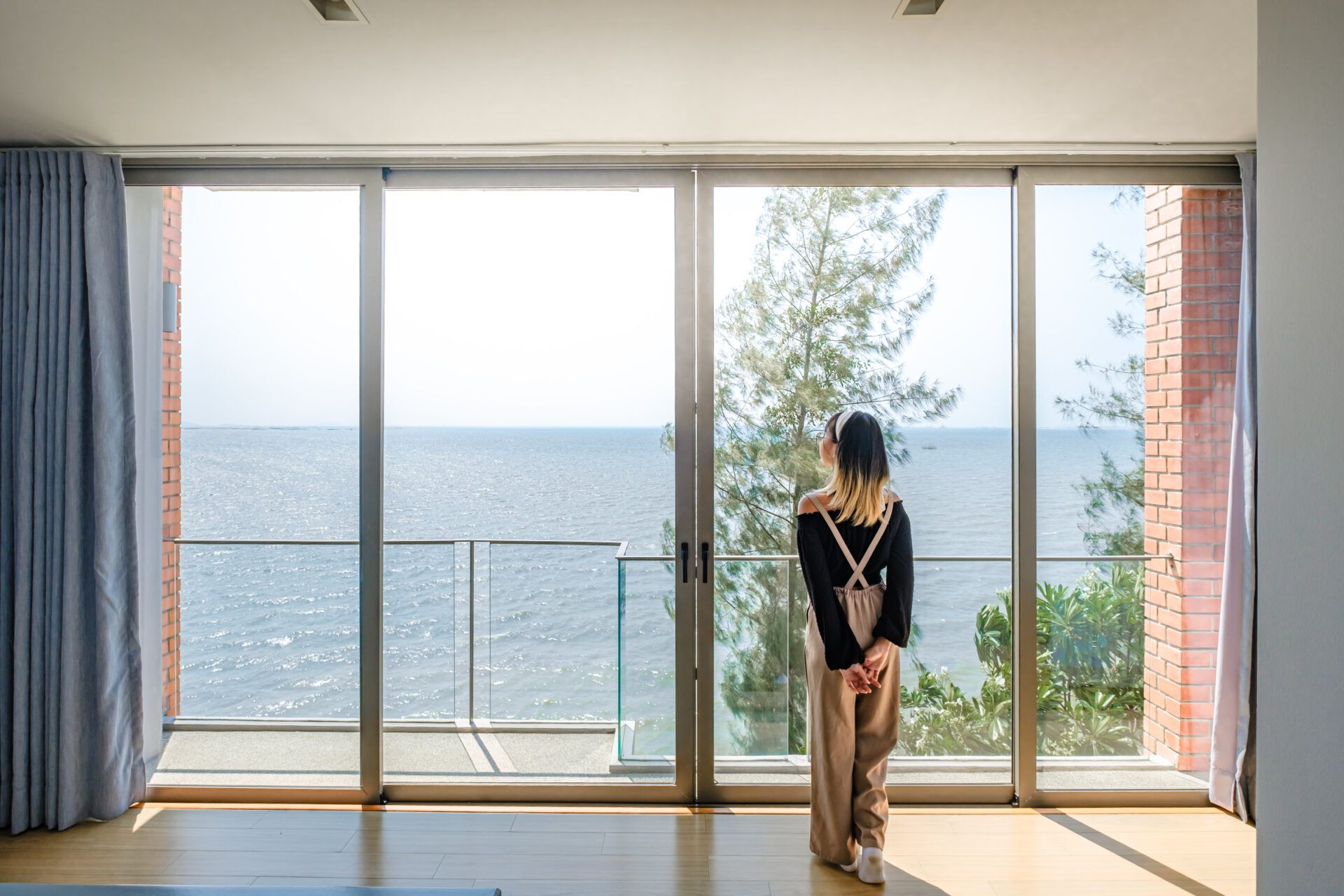 Ocean view from Sand Beachfront Villa IV, พัทยาเหนือ บางละมุง. Woman looks out large window at the sea.