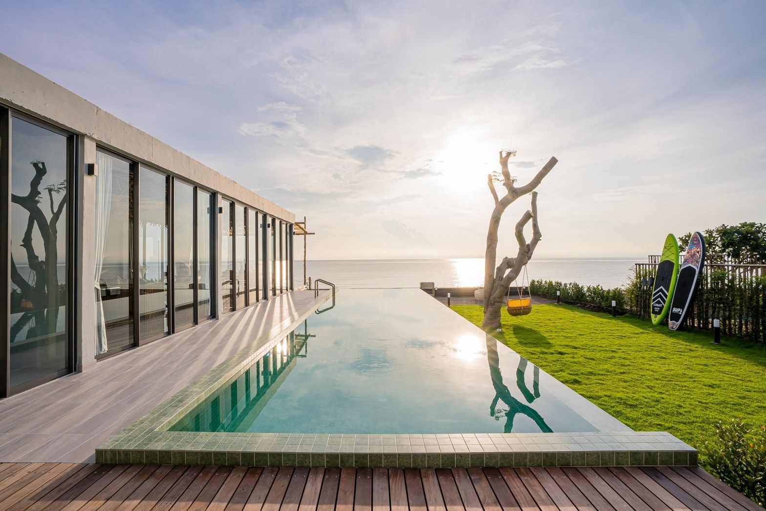 Sea Fan IV beachfront pool villa near Huahin airport. Infinity pool reflects the sky and ocean. Paddleboards on the lawn.