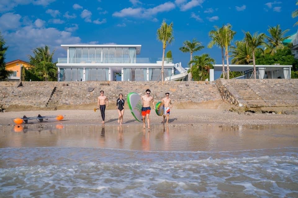 Sea Lion VIII pool villa, หาดชะอำเหนือ เพชรบุรี, Thailand. Group of friends on the beach with paddleboards in front of the vi