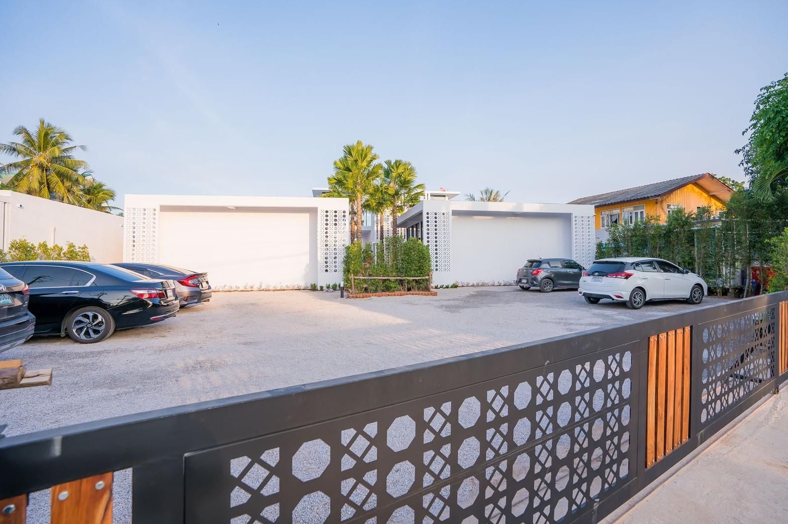 Sea Lion VIII Pool Villa parking area in หาดชะอำเหนือ เพชรบุรี. Cars parked behind a decorative metal and wood gate.