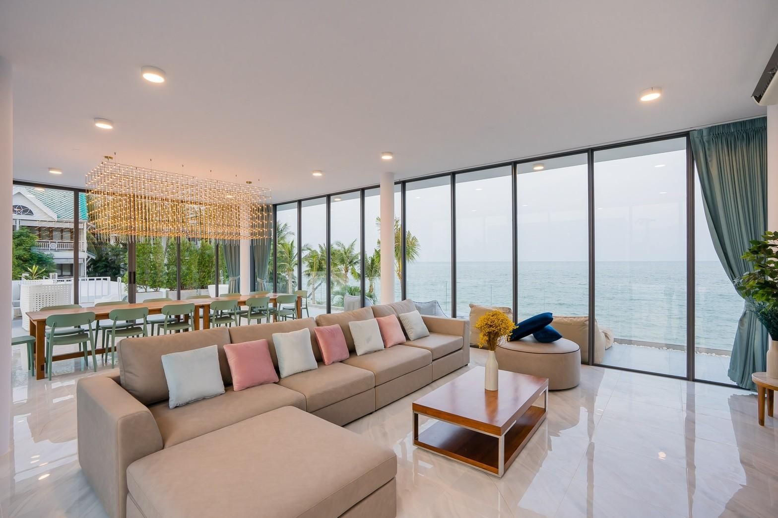 Spacious living room with ocean view at Sea Lion VIII Pool Villa, หาดชะอำเหนือ เพชรบุรี. Large sofa and dining table visible.