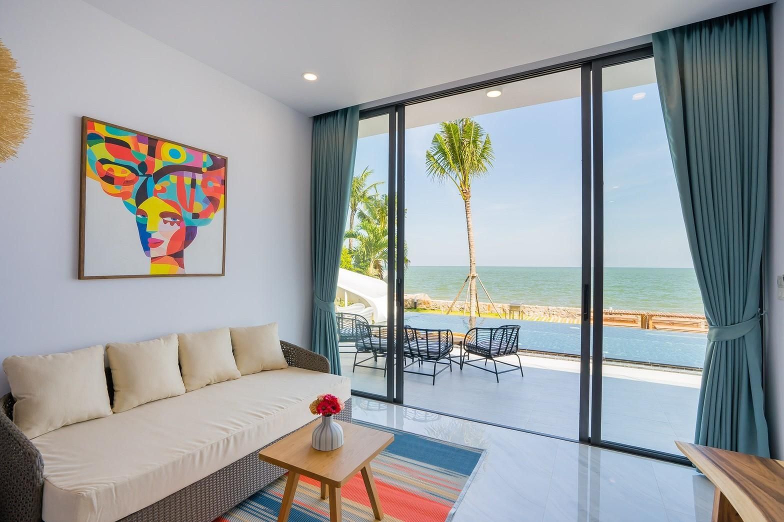 Living room with ocean view at Sea Lion VIII Pool Villa, Cha-am. Sofa, table, and colorful artwork visible.
