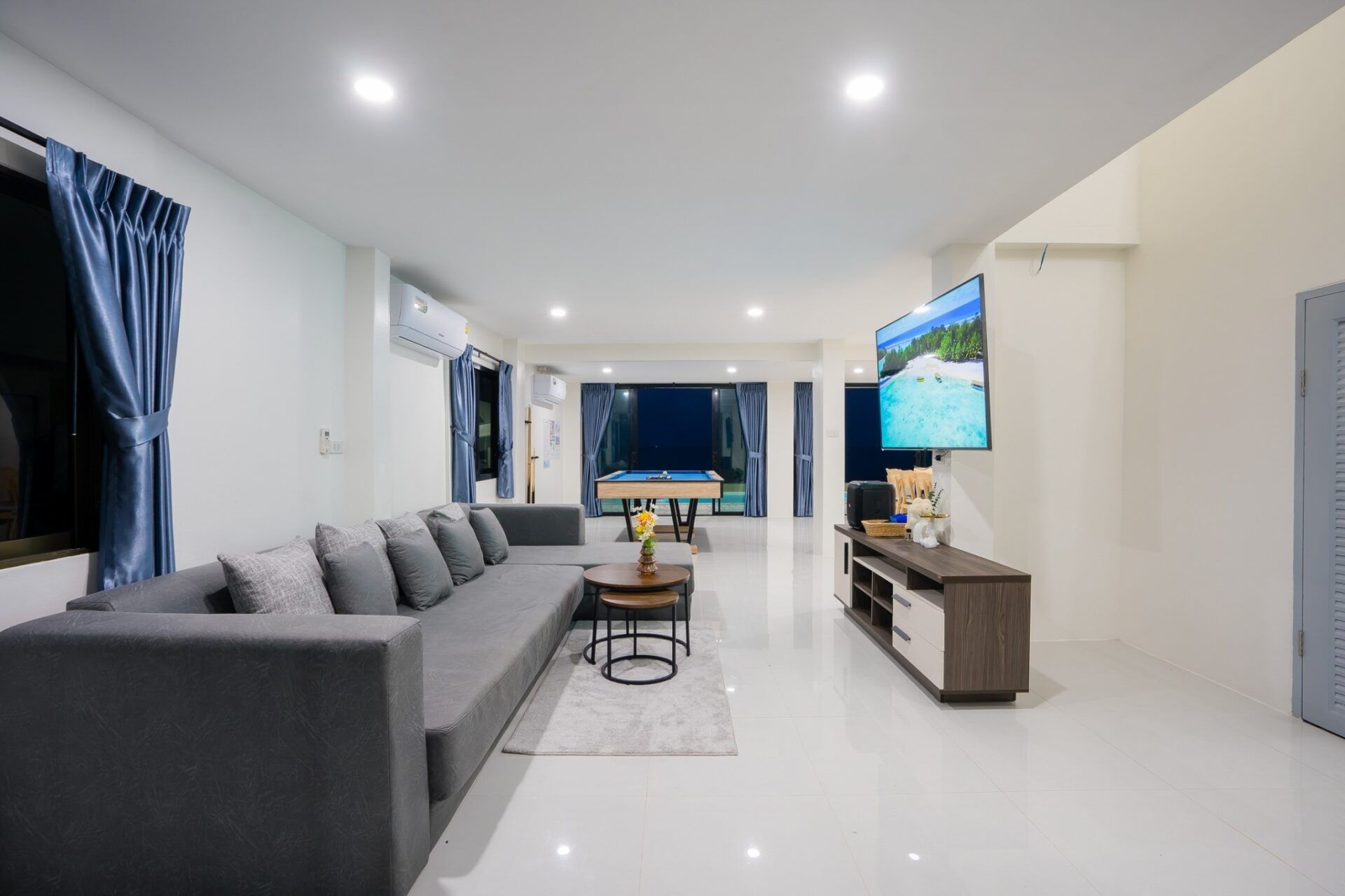 Modern living room with gray sofa and pool table at Sea Time V Pool Villa, Cha-Am, Thailand.