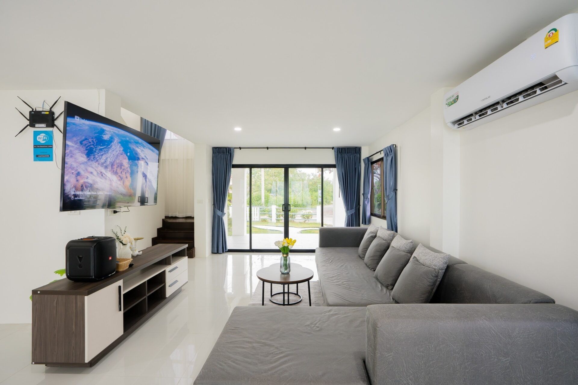 Bright living room with large gray sofa at Sea Time V Pool Villa, Cha-Am, Thailand.