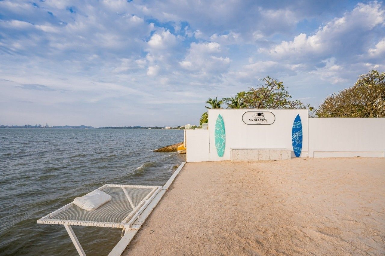 Beachfront hammock at Sea View IV Pool Villa, Pattaya. Surfboards decorate the wall near the sea.