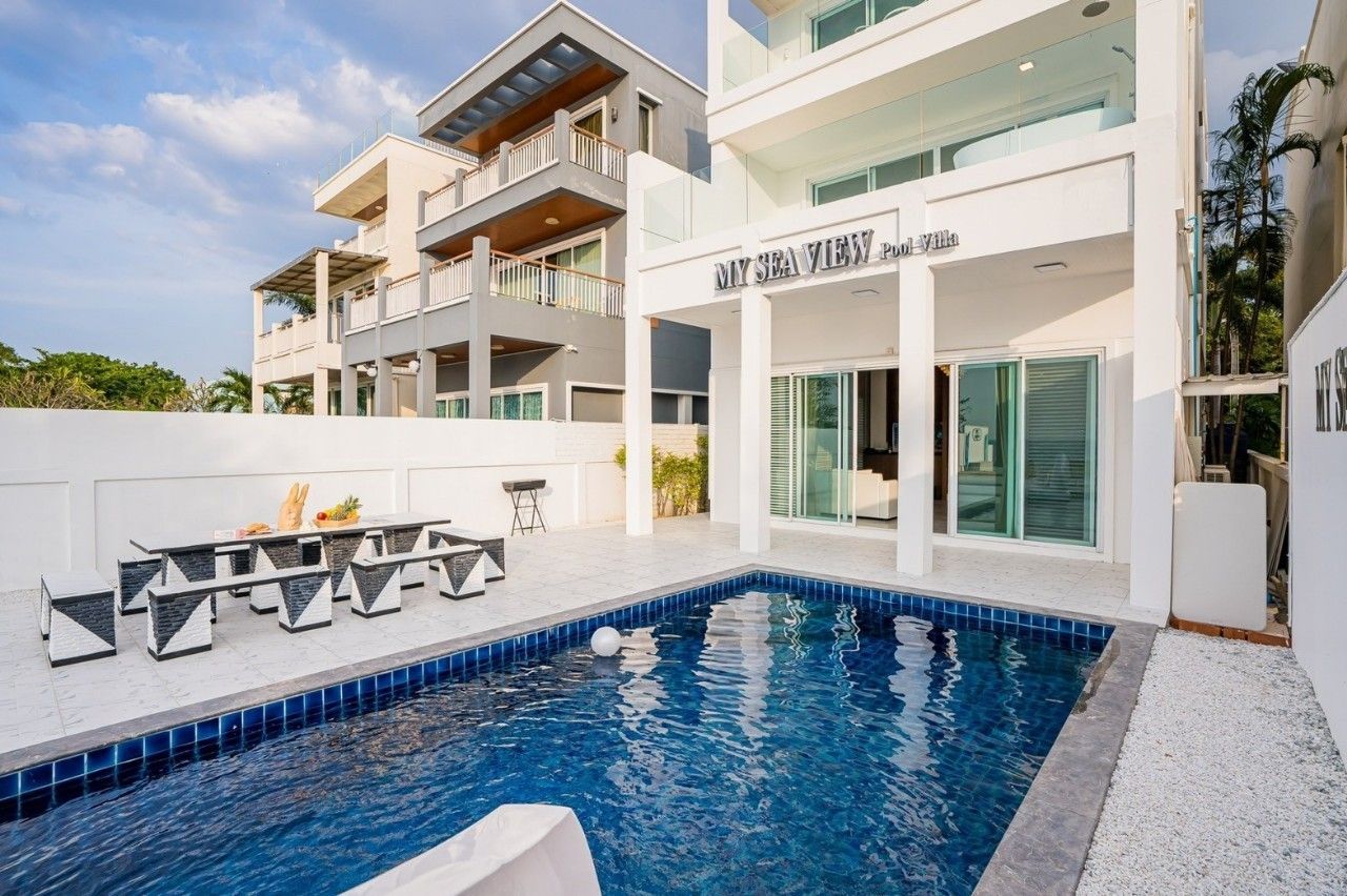 Inviting pool at Sea View IV Pool Villa, Pattaya. Outdoor dining table and benches next to the pool.
