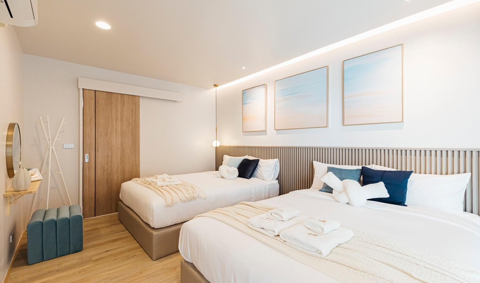 Twin beds with blue accents and beach artwork in a bedroom at SHORE SEASON V Pool Villa, Banglamung, Pattaya.