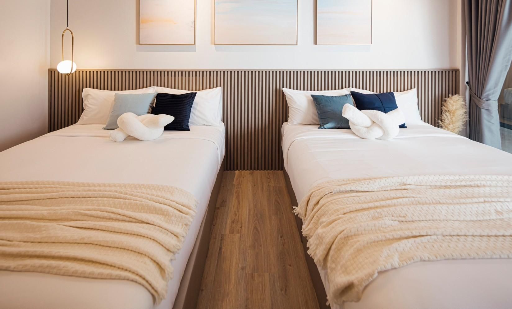 Twin beds with decorative pillows at SHORE SEASON V POOL VILLA, Banglamung, Pattaya. Modern headboard and neutral decor.