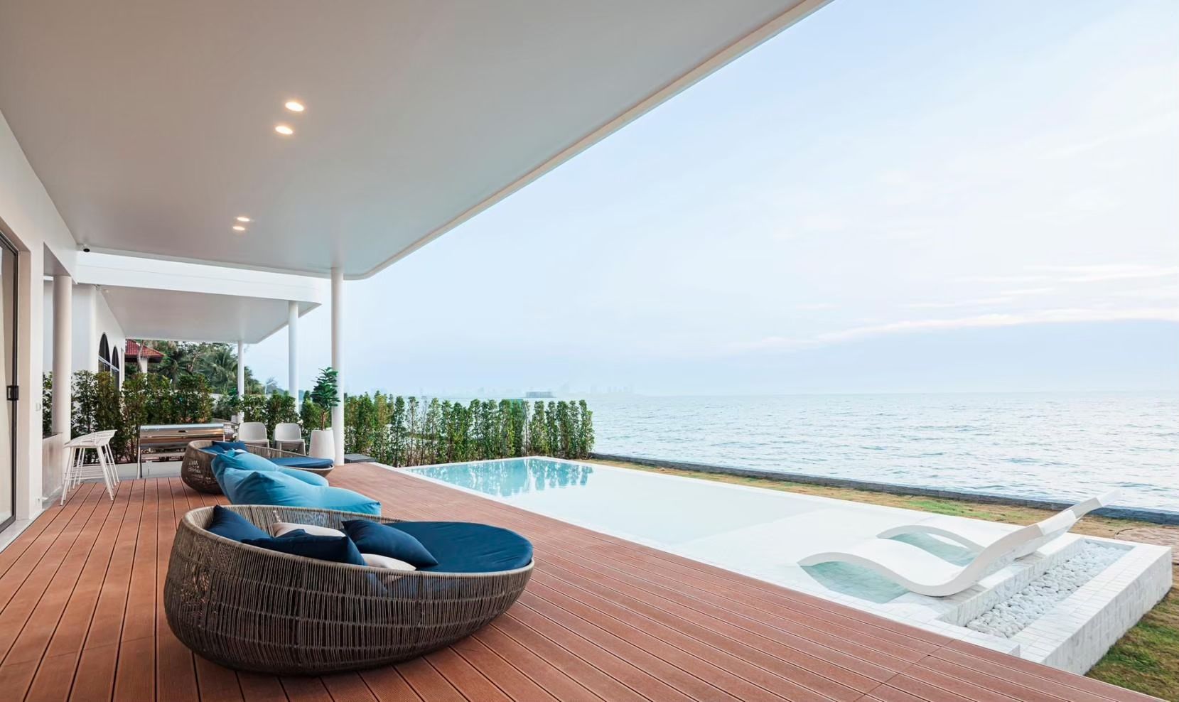 SHORE SEASON V Pool Villa in Banglamung, Pattaya. Infinity pool overlooks the ocean with lounge chairs and outdoor seating.