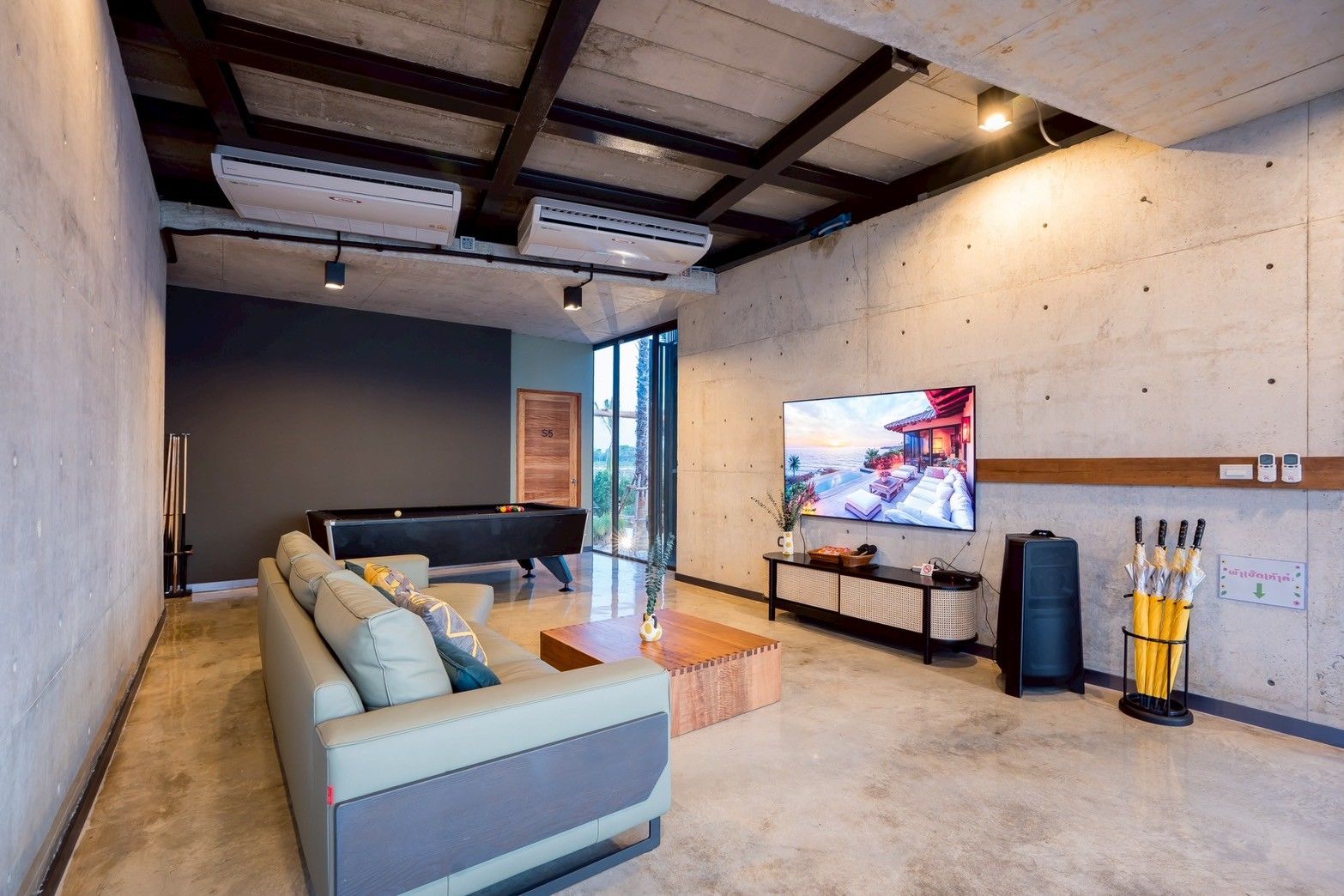 Living room at Spirit V Pool Villa, หาดปึกเตียน-ชะอำ. Features a pool table, large TV, and modern concrete walls.