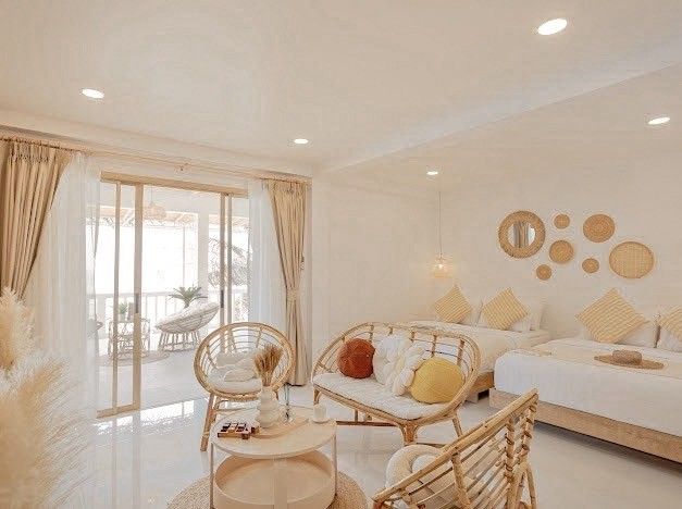 Bright bedroom at Story II Pool Villa Hua-Hin. Rattan chairs, sofa, and two beds with yellow pillows. Balcony view.