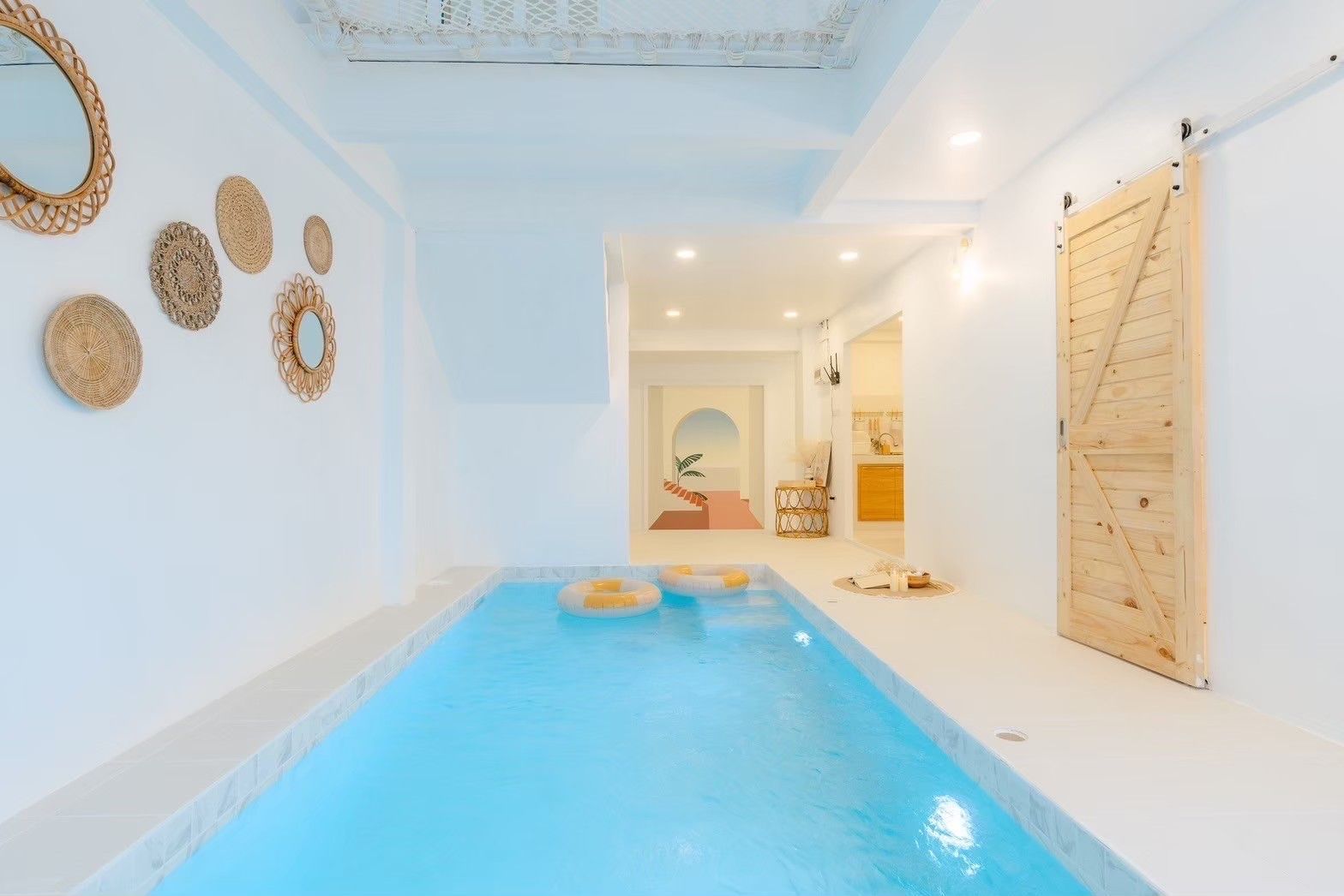 Indoor pool with floaties at Story II Pool Villa Hua-Hin, เขาเต่า-หัวหิน. Modern design with a wooden barn door.