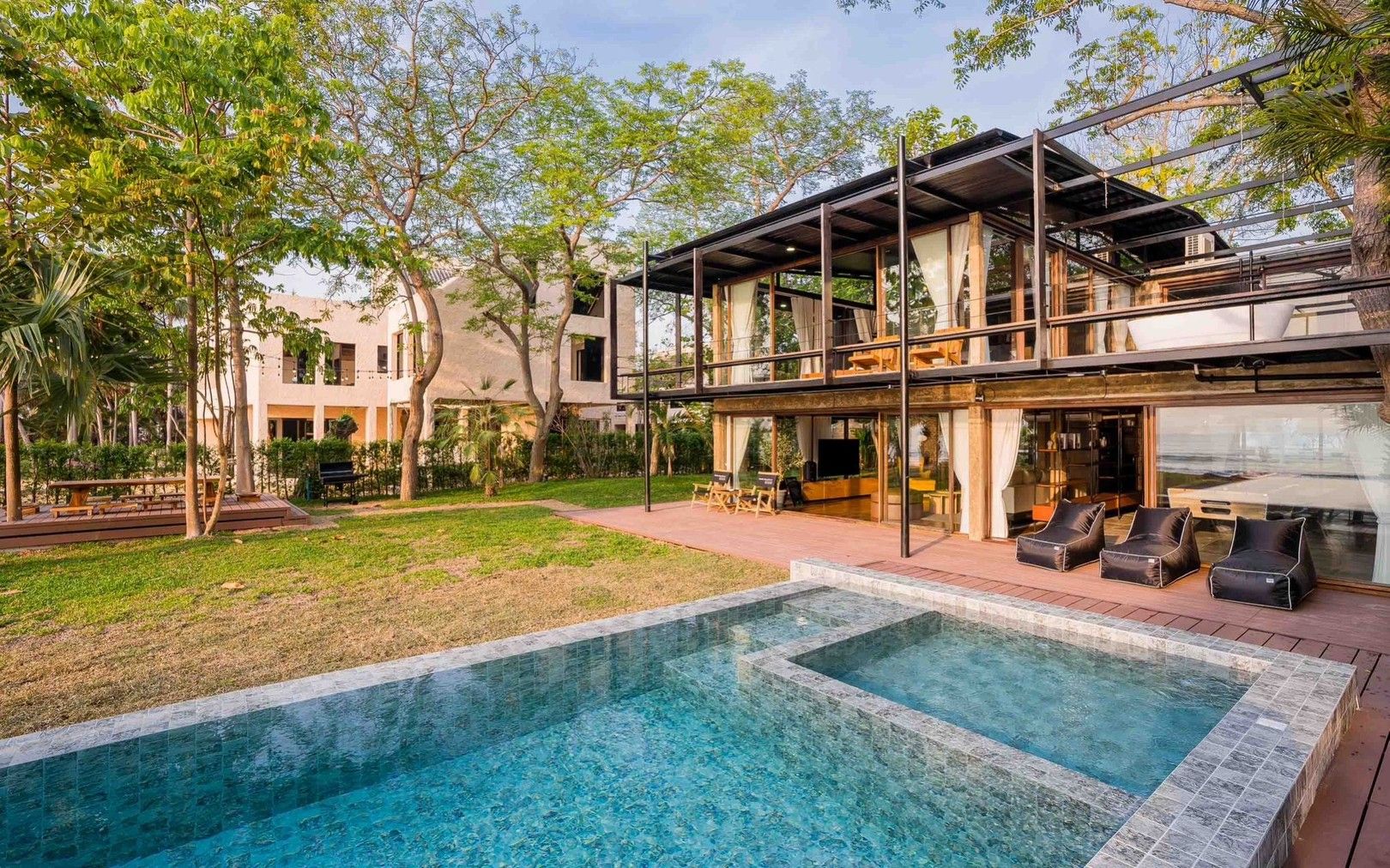 Studio Beachfront III pool villa, หาดปึกเตียน ชะอำ. View of the mosaic tile pool and modern villa exterior from the lawn.