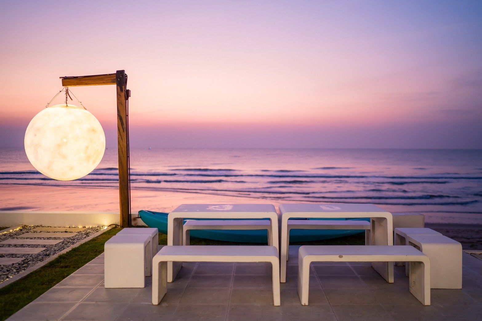 Sunset view from the beachfront dining area at Sun Sea V Pool Villa, Cha Am. Modern white table and benches.