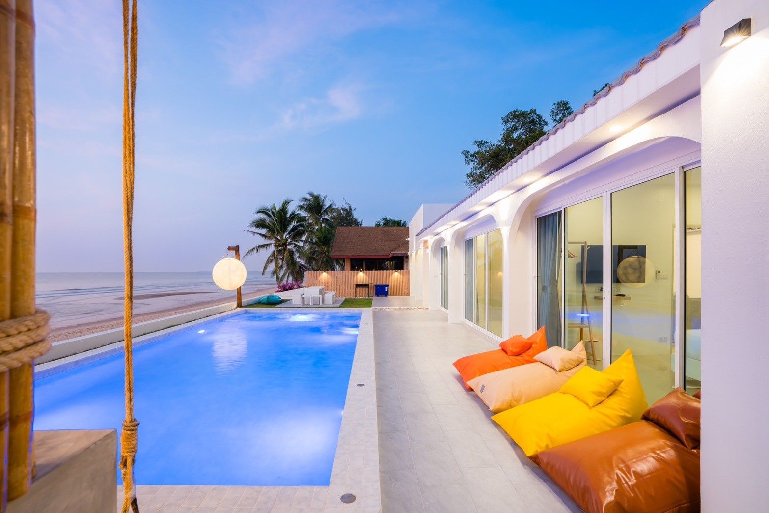 Sun Sea V Pool Villa beachfront pool at dusk in Cha Am. Colorful beanbag chairs line the pool deck.