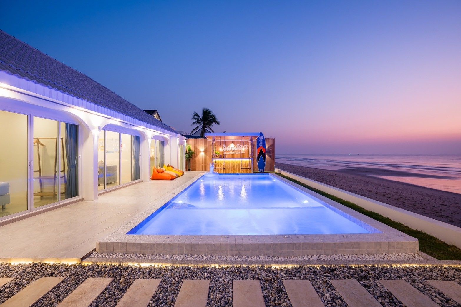 Sun Sea V Pool Villa beachfront pool at dusk in Cha Am, Thailand. Features a swim-up bar and ocean views.