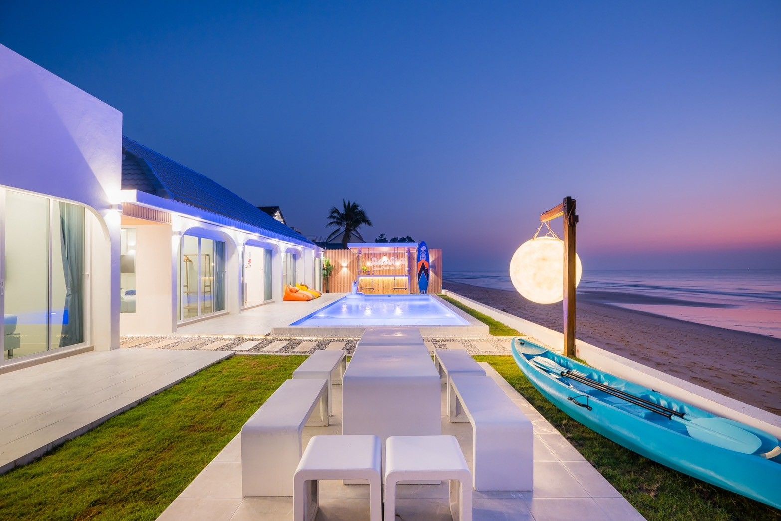 Evening view of the pool and beach at Sun Sea V Pool Villa, ติดทะเล หาดบางเกตุ ชะอำ. Kayak and outdoor dining visible.