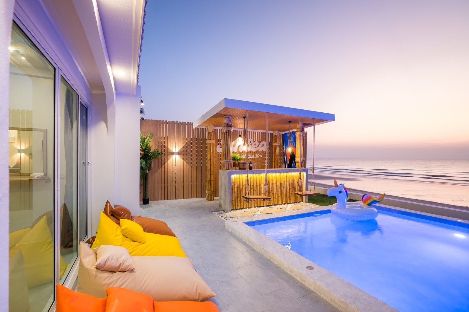 Sun Sea V Pool Villa in Cha Am has a poolside bar and unicorn floatie in the pool at sunset.