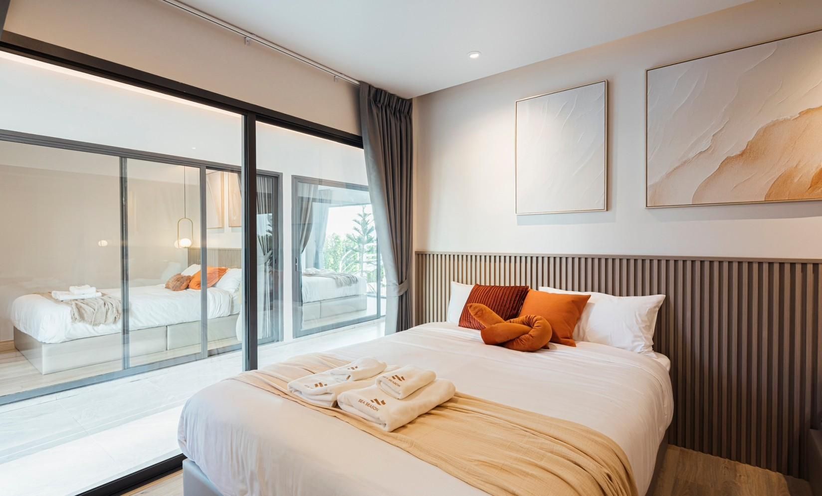King bed with orange pillows at Sun Season V Pool Villa, Banglamung, Pattaya. View through glass to another bedroom.