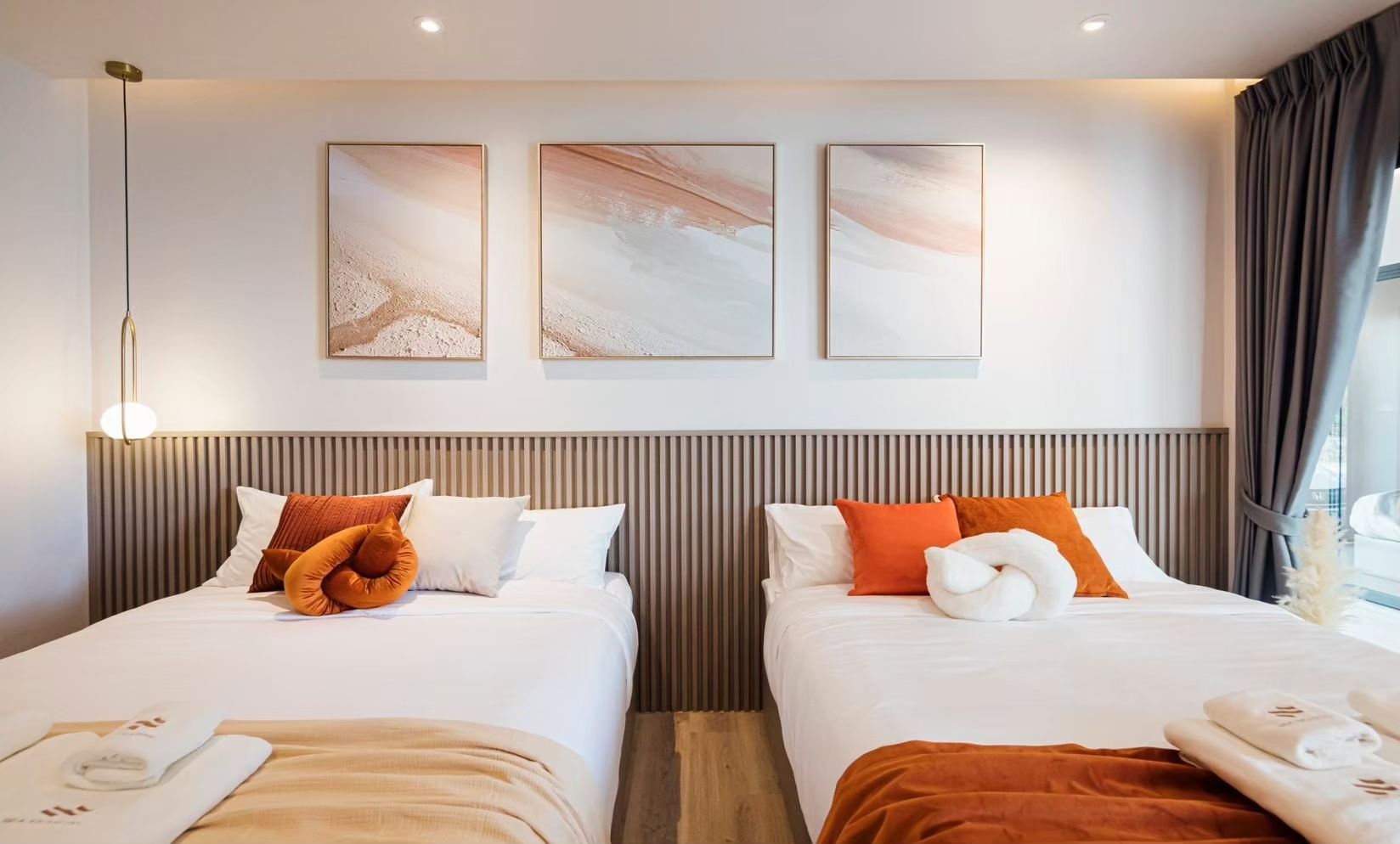 Twin beds with orange pillows and modern art at SUN SEASON V Pool Villa, Banglamung, Pattaya.