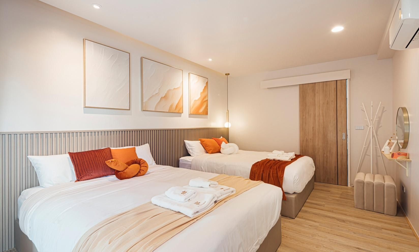 Twin beds with orange accents in a bedroom at SUN SEASON V Pool Villa, Banglamung, Pattaya. Modern decor and artwork.