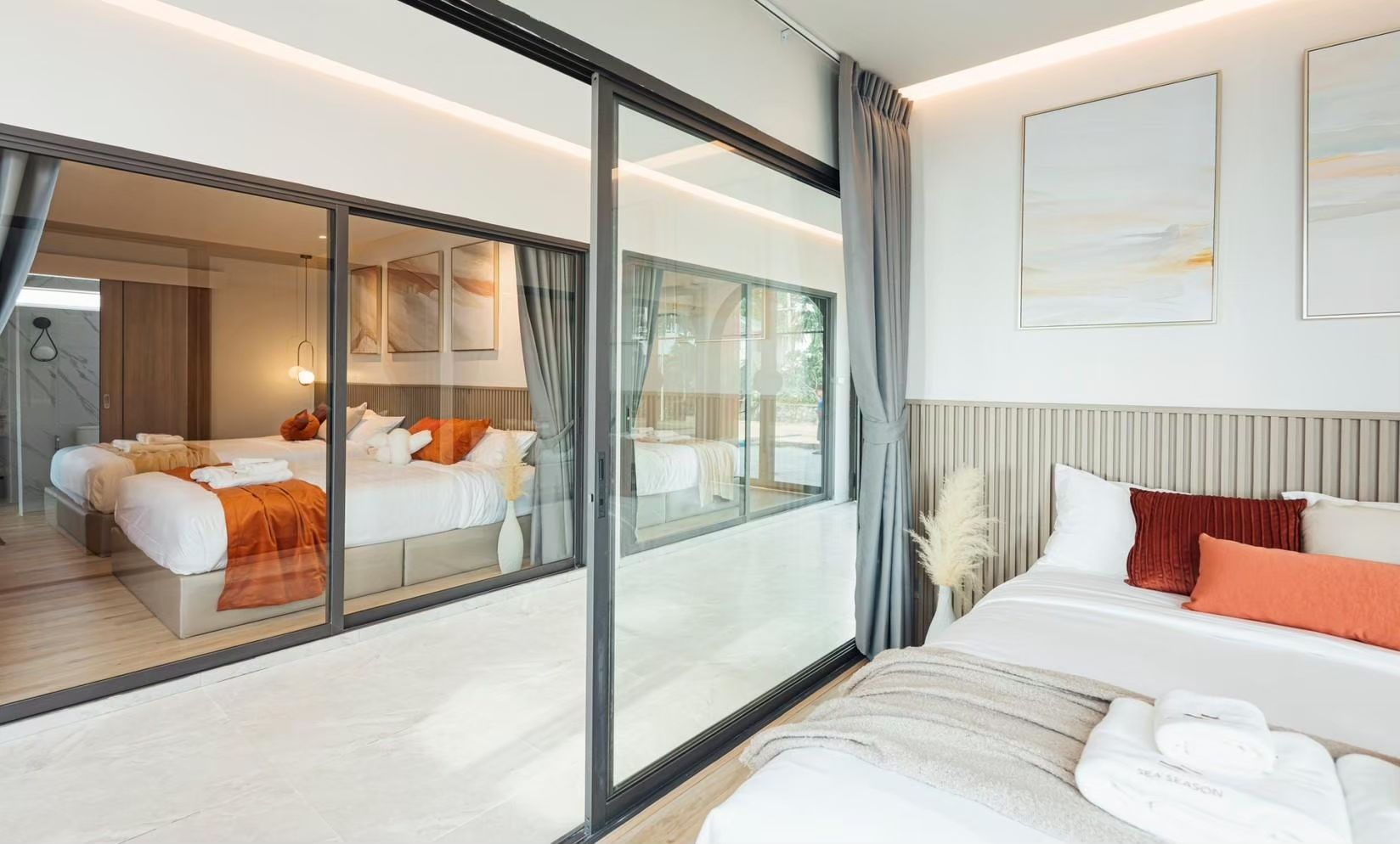 Twin beds and balcony view at SUN SEASON V Pool Villa, Banglamung. Modern bedroom with white linens and orange accents.