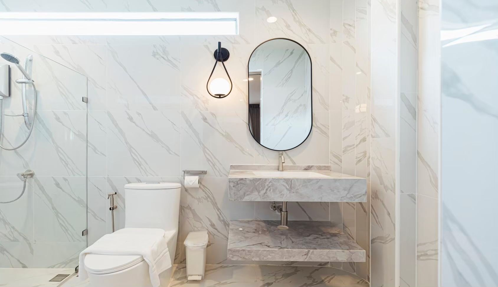 Bathroom with marble wall and floating sink at SUN SEASON V POOL VILLA, Banglamung, Pattaya. Modern oval mirror and shower.