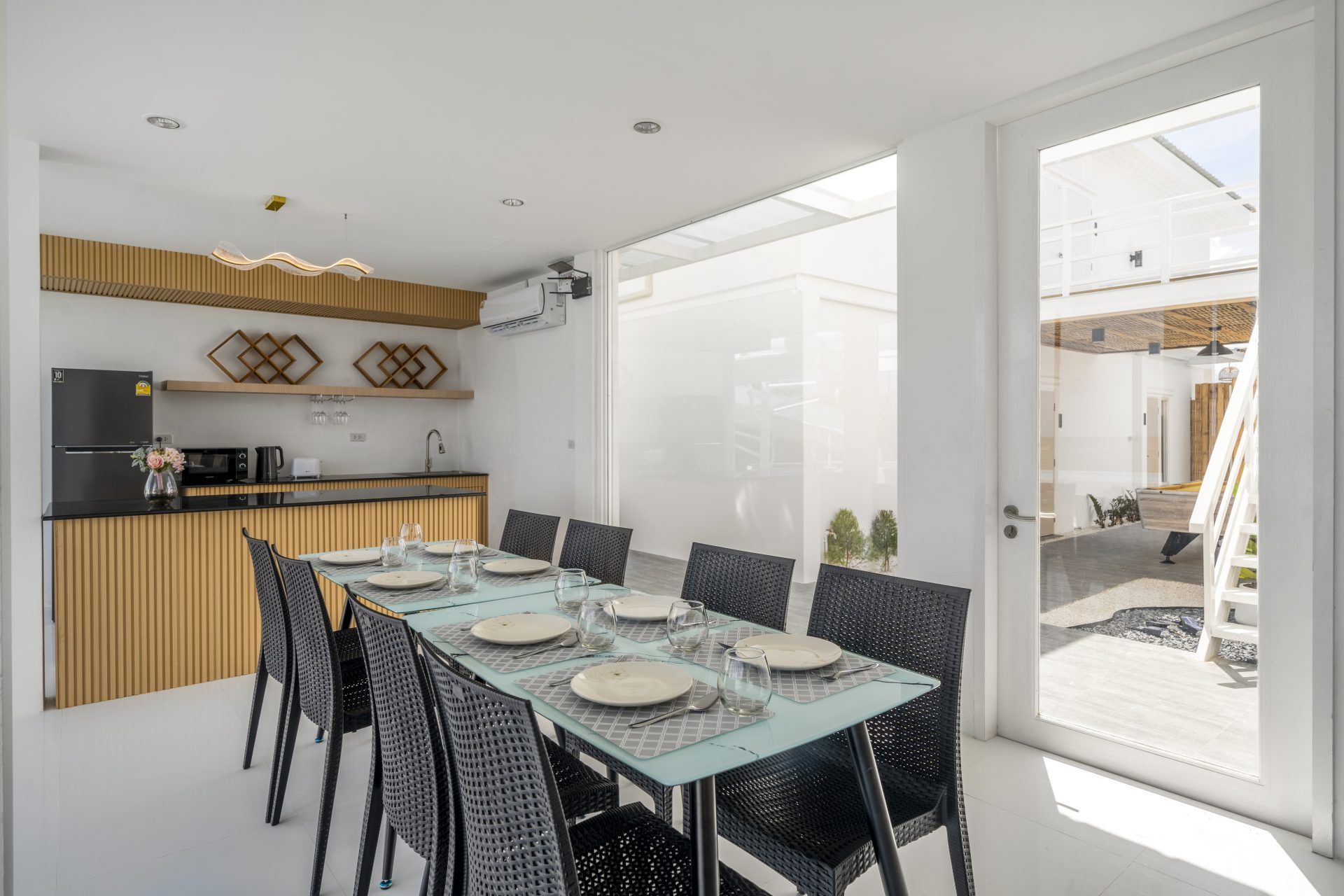 Talay Haus X Pool Villa dining area, หาดเจ้าสำราญ-ชะอำ เพชรบุรี. Table set for 8 with modern black wicker chairs.