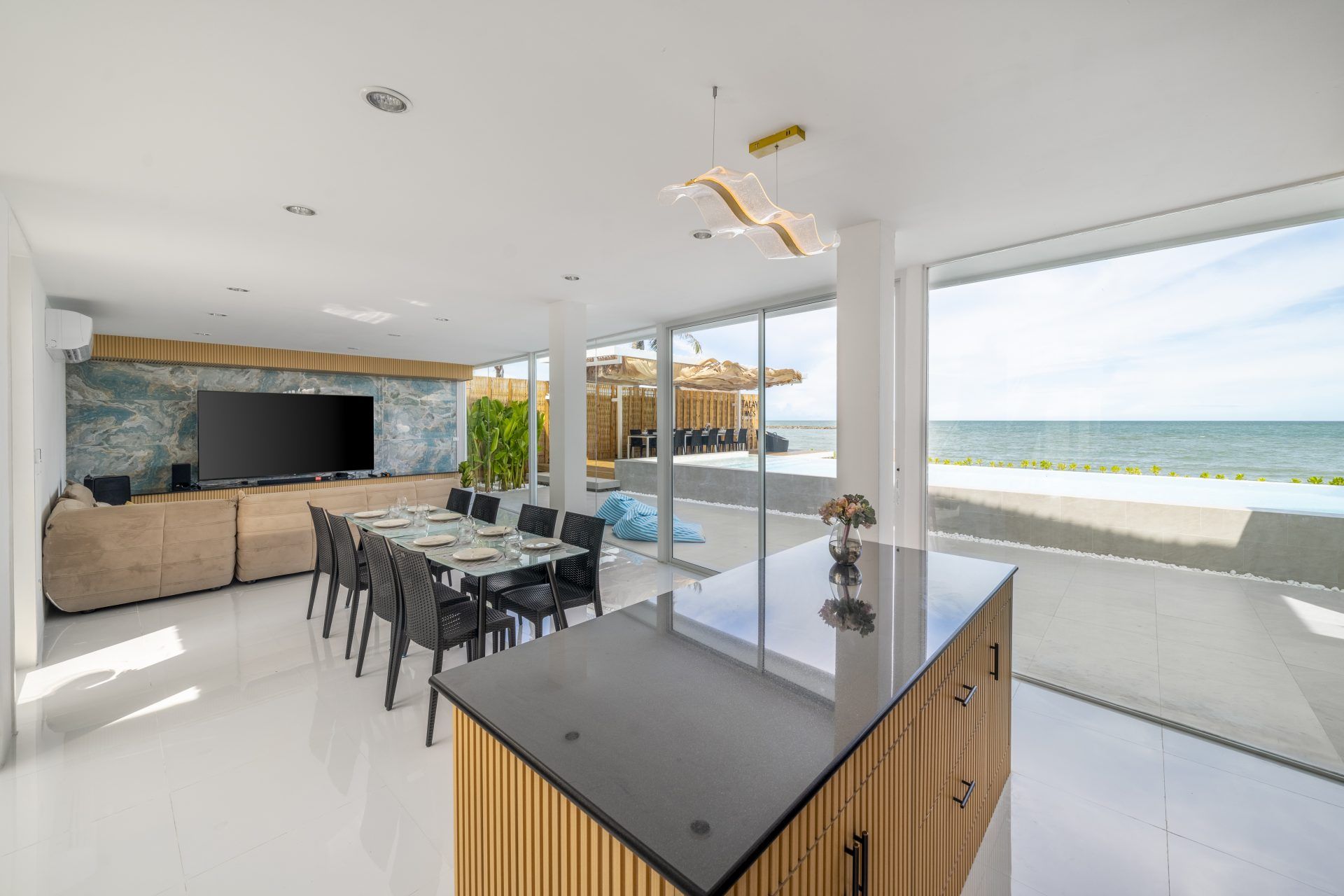 Dining area with ocean view at Talay Haus X Pool Villa, หาดเจ้าสำราญ-ชะอำ เพชรบุรี. Table set for 8, modern lighting.
