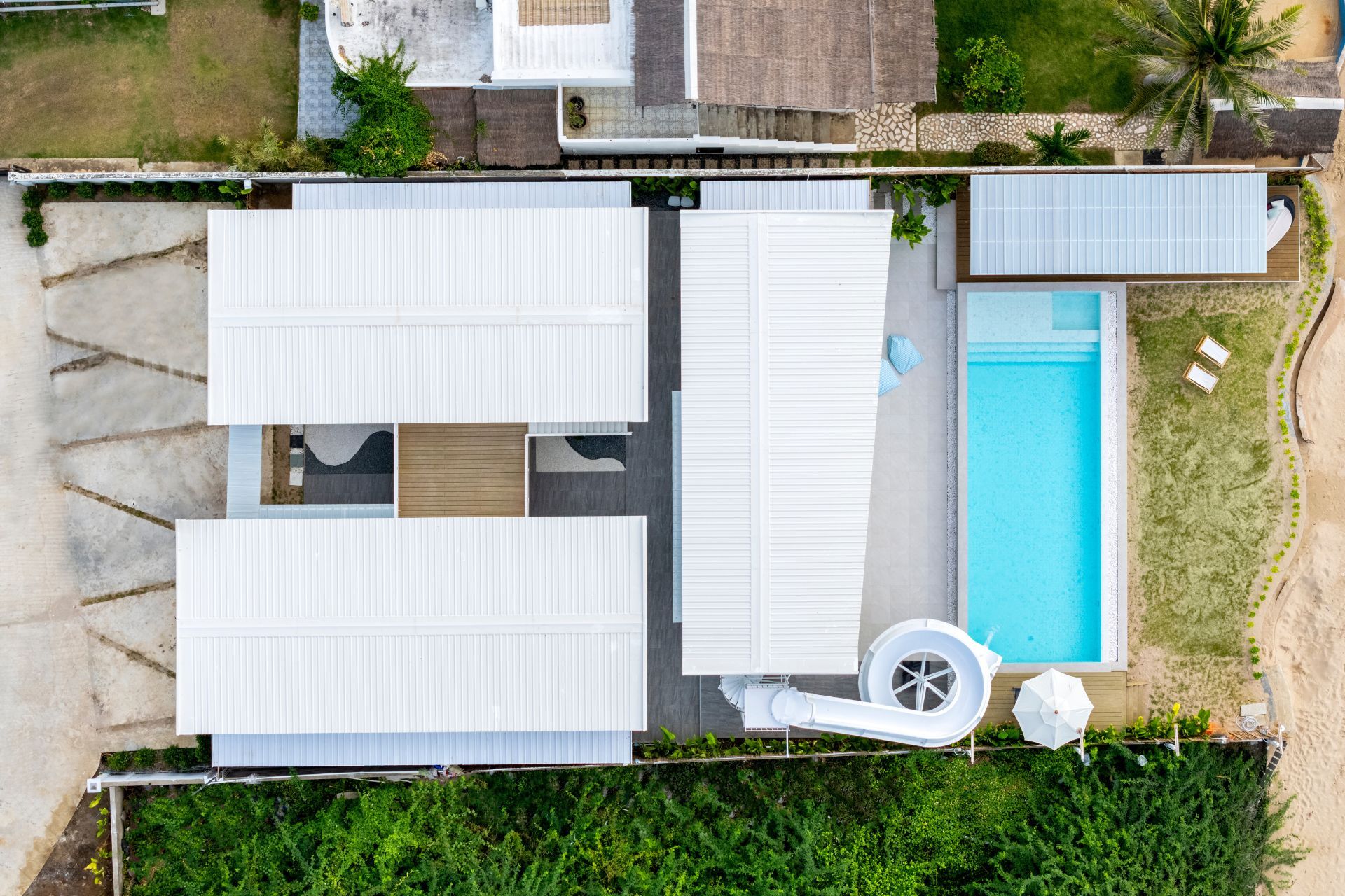 Aerial view of Talay Haus X Pool Villa, หาดเจ้าสำราญ-ชะอำ เพชรบุรี. Modern architecture, pool, and waterslide visible.