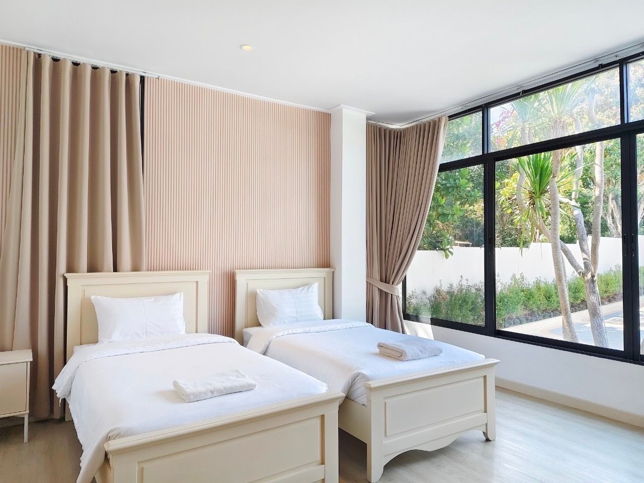 Twin single beds in a bright bedroom at The Valley Khao Yai II pool villa, Khao Yai. View of the garden.