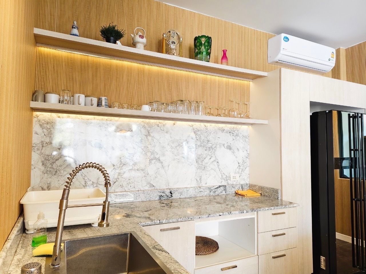 Kitchen area with marble backsplash and open shelving at The Valley Khao Yai II pool villa, Khao Yai, Thailand.