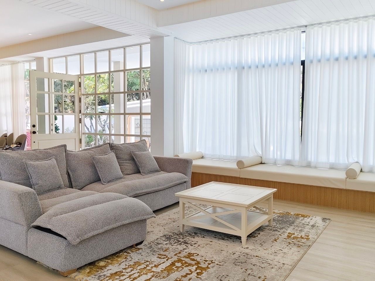 Living room with sectional sofa and window seat at The Valley Khao Yai II pool villa, Khao Yai, Thailand.
