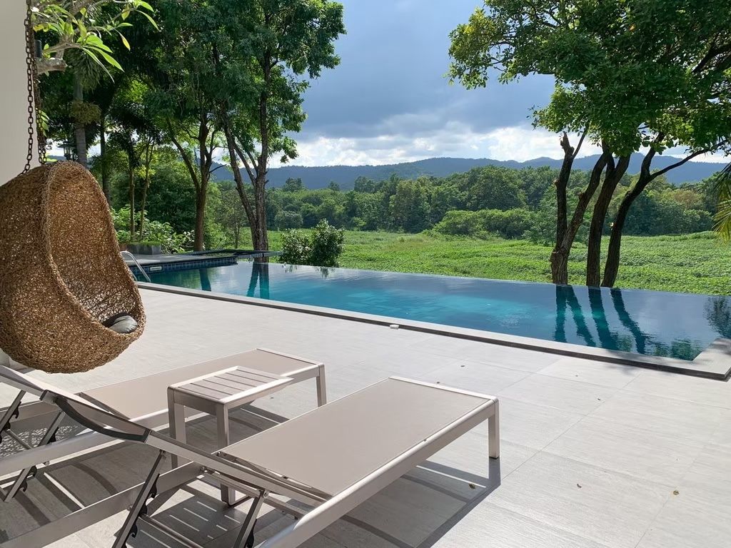 Infinity pool and hanging chair at The Valley Khaoyai I pool villa, หมูสี เขาใหญ่, Thailand. Overlooking green valley.