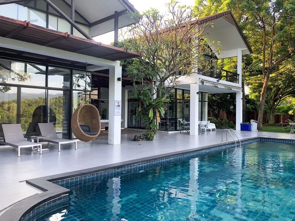 The Valley Khaoyai pool villa. View of the pool with lounge chairs and hanging chair on the patio. หมูสี เขาใหญ่.