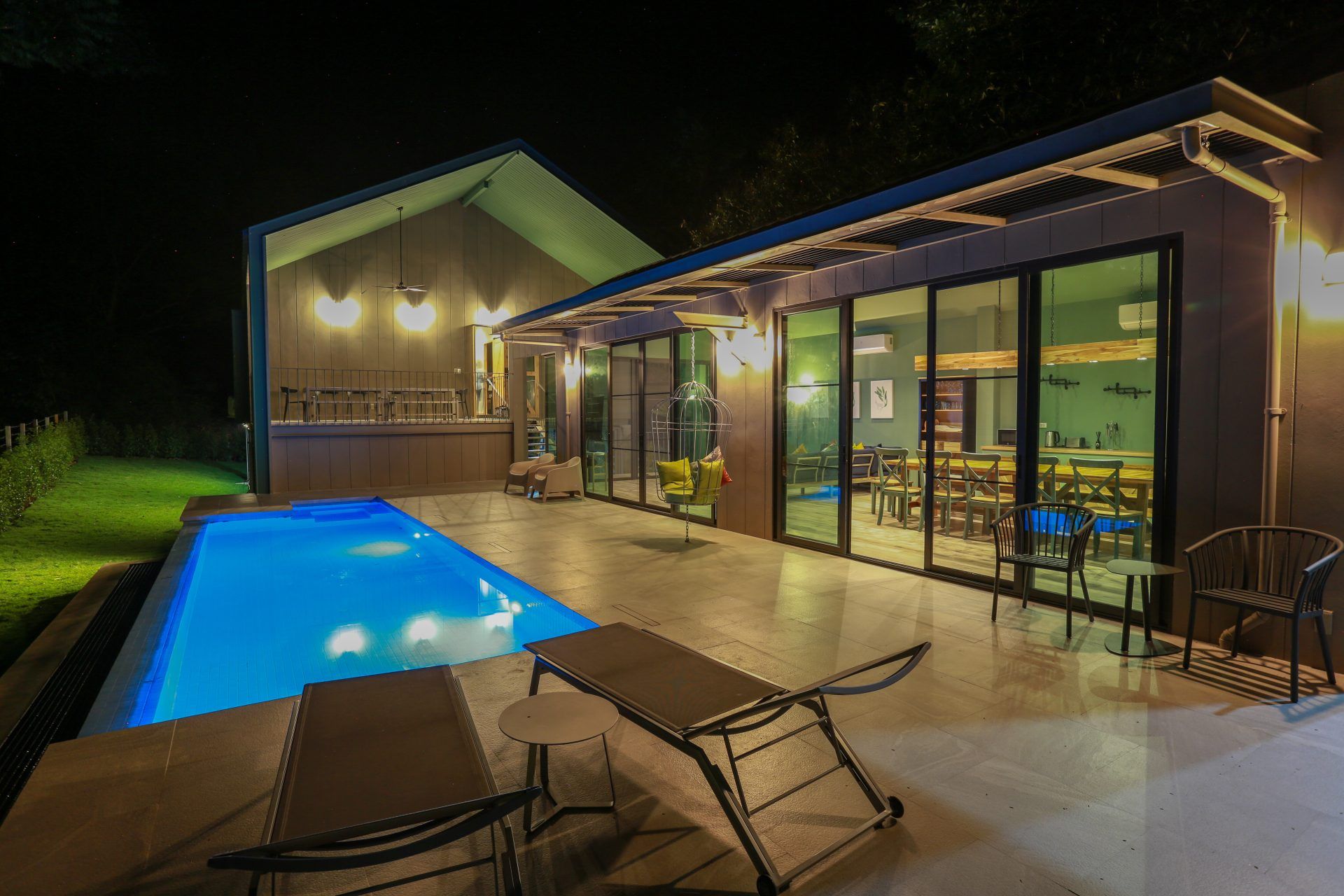 Night view of the illuminated pool at The Valley Khaoyai VI Villa, หมูสี เขาใหญ่. Lounge chairs visible.