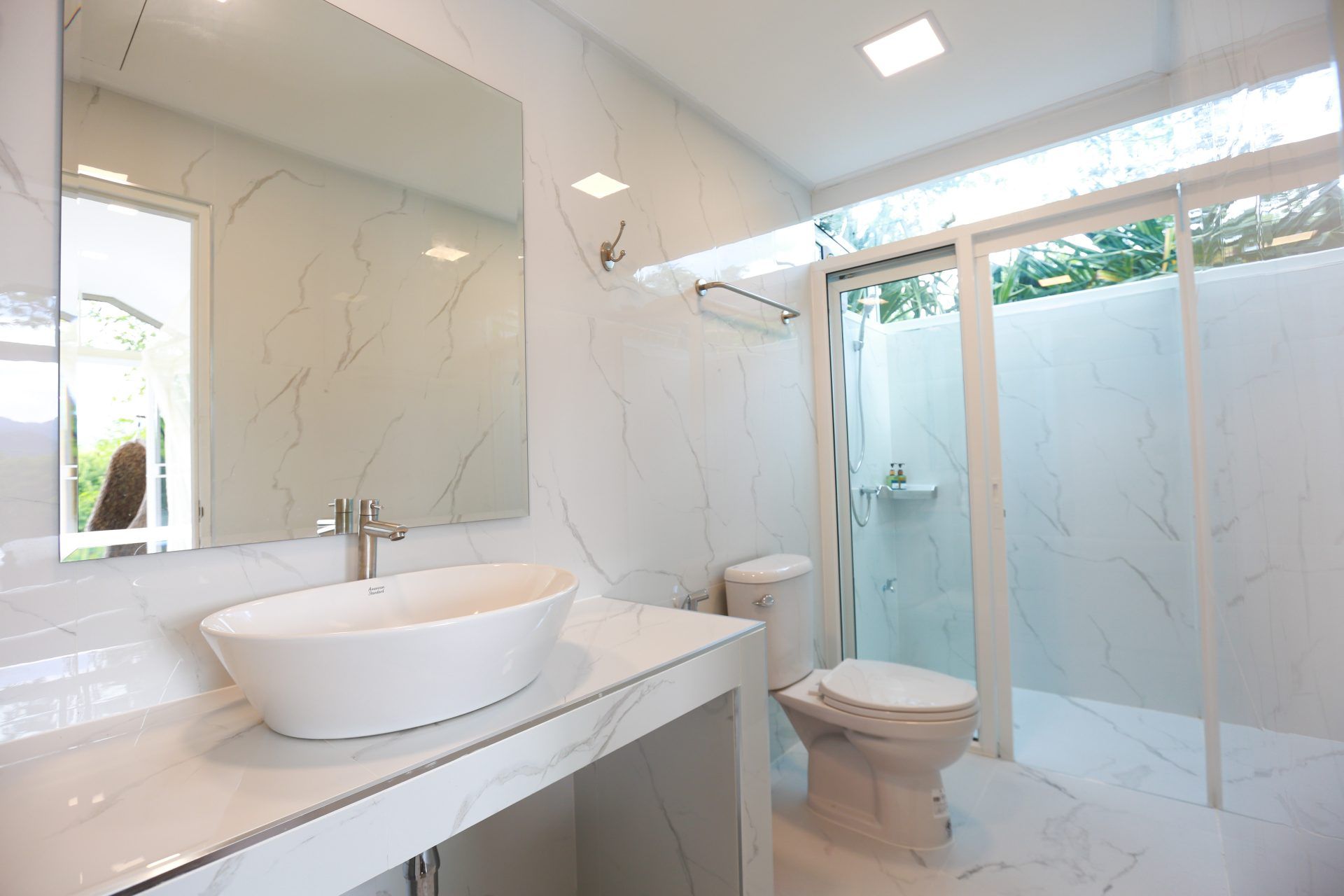 Bright bathroom with marble walls and glass shower at Tree House III Pool Villa, Khao Yai. Modern fixtures and clean design.