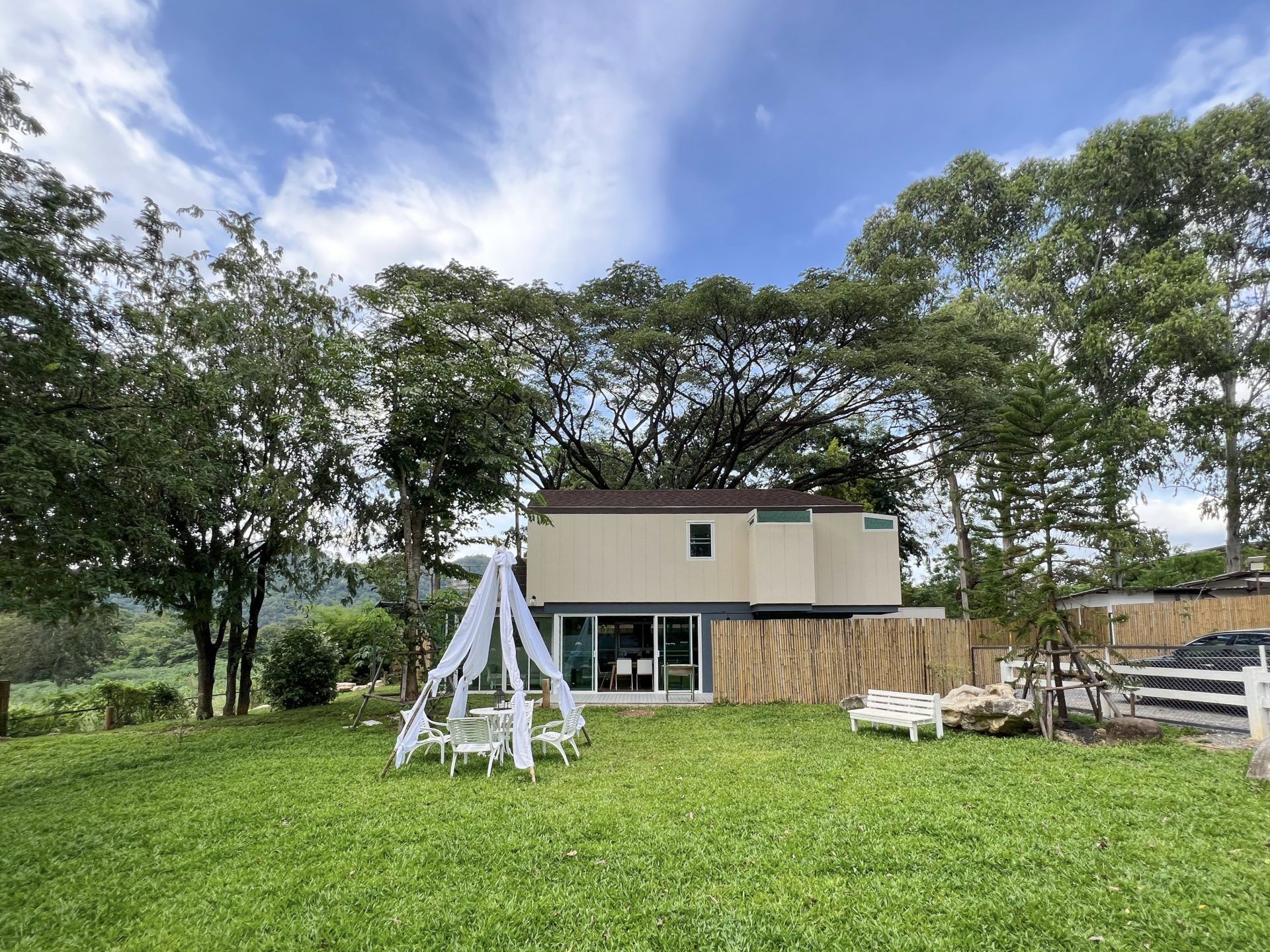 Lawn seating area at Tree House III Pool Villa, Khao Yai. Tent-like canopy over outdoor table and chairs.