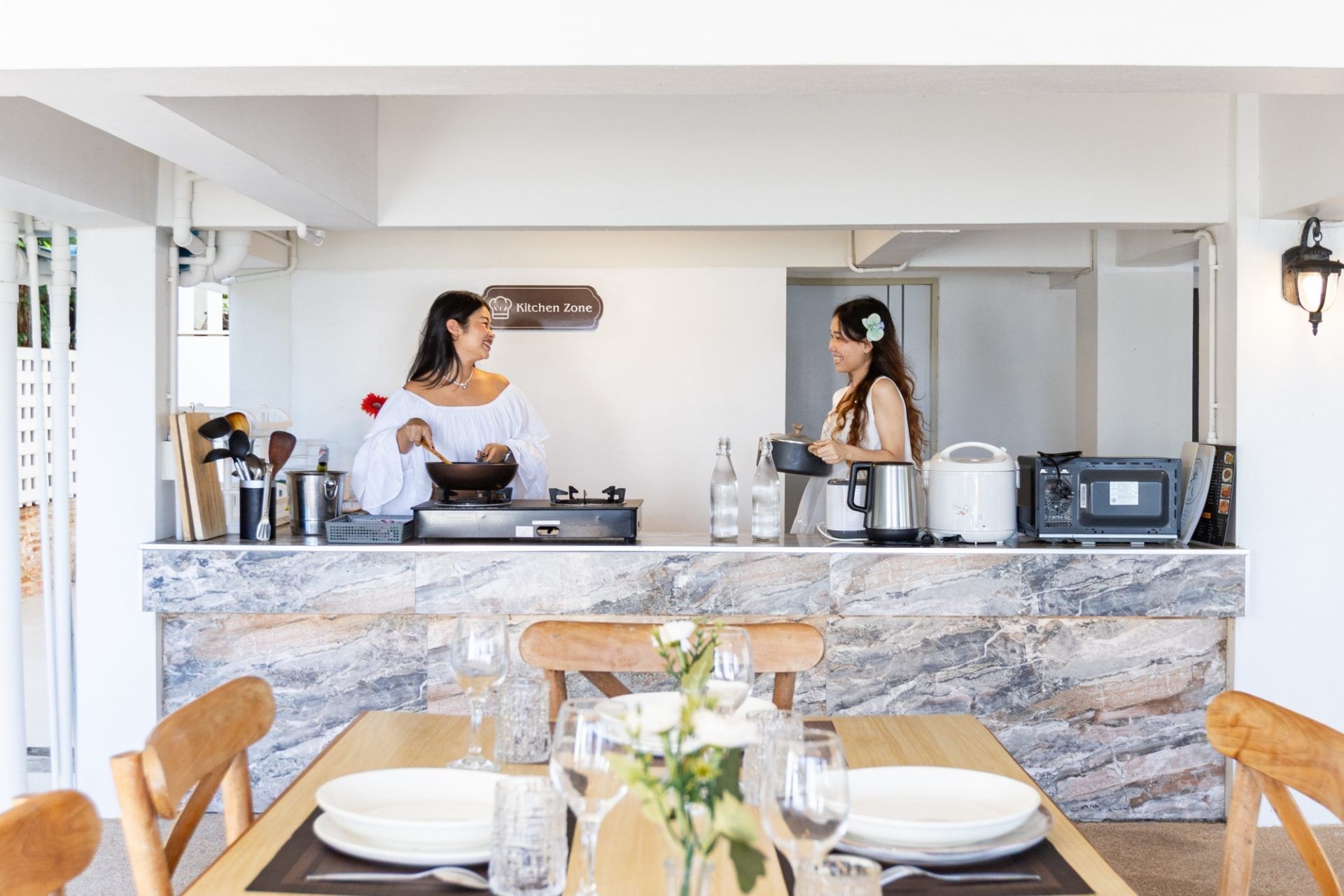 Dining table and kitchen at Twenty-Six Pool Villa Hua-hin. Two women cooking and setting the table in ประจวบฯ.