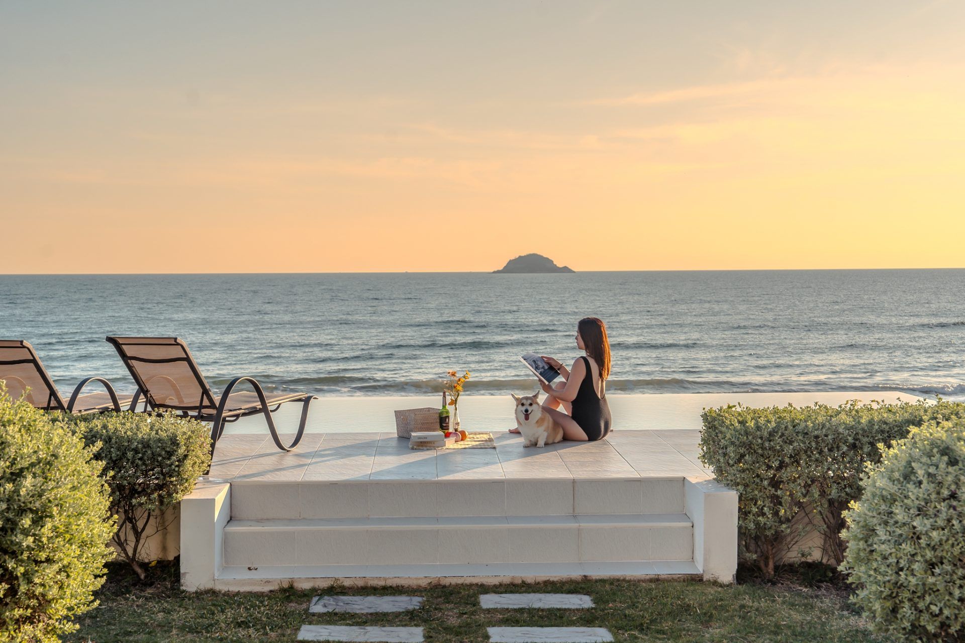 Twenty-Six Pool Villa Hua-hin beachfront infinity pool with woman and dog enjoying the ocean view at sunset. หัวหิน 101 ประจว