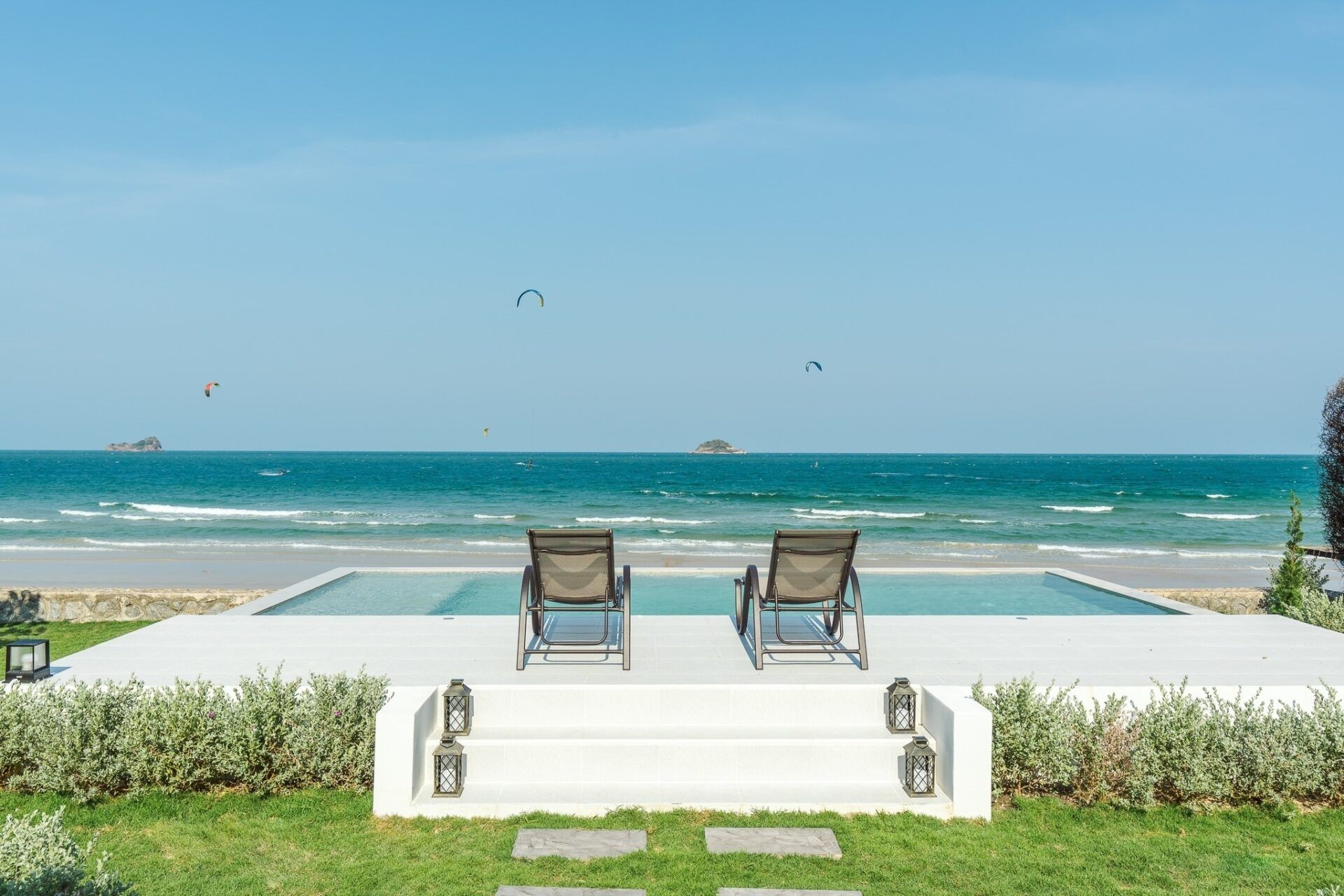 Beachfront infinity pool and lounge chairs at Twenty-Six Pool Villa Hua-hin, หัวหิน 101 ประจวบฯ. Ocean view with kitesurfers.