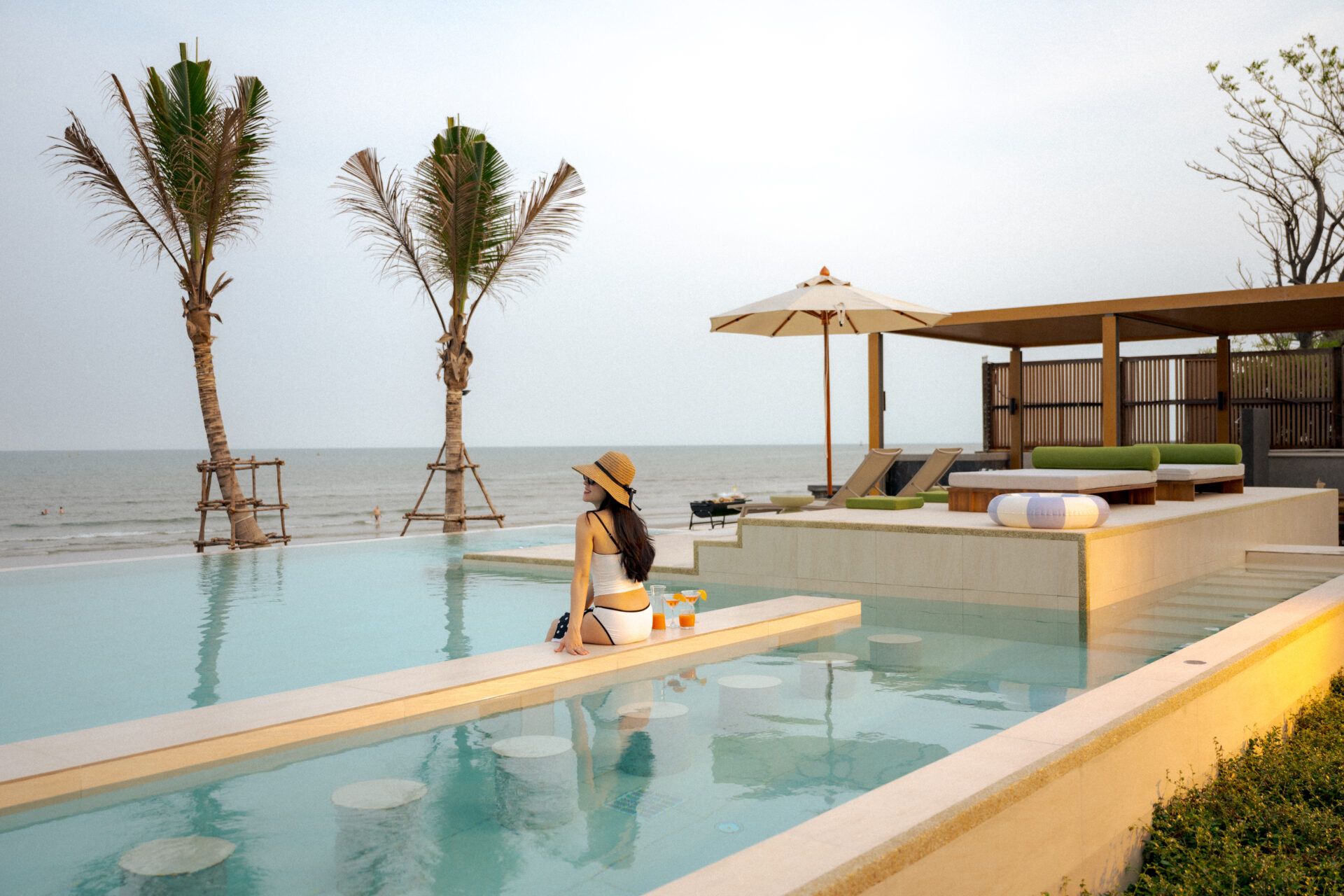 Woman at swim-up bar in Valika VIII pool villa, Hua Hin. Enjoy cocktails by the infinity pool overlooking the ocean.